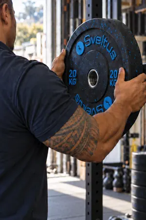 Technicien Tahitian Indoor Sports chargeant un disque Sveltus de 20 kg sur une barre de rack en Polynésie française