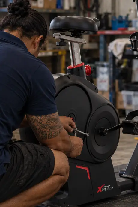 Technicien Tahitian Indoor Sports réglant un vélo d’appartement BH Fitness dans l’atelier de Punaauia